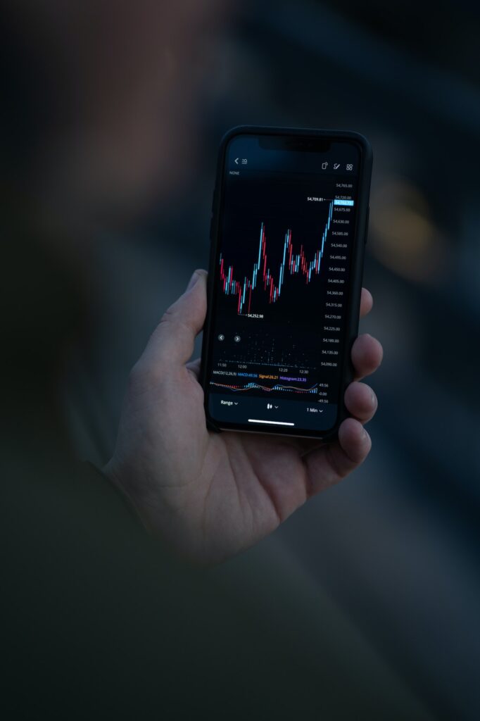 Businessman trader looking at stock market data on smartphone screen and analyzing forex chart